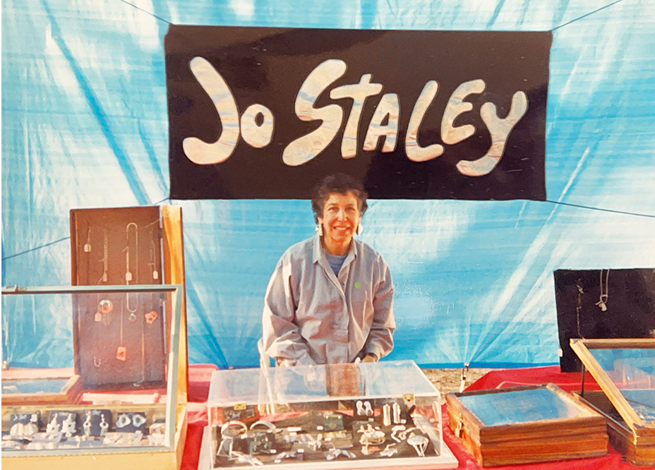 Jo behind her jewelry booth with a hand-painted Jo Staley banner.