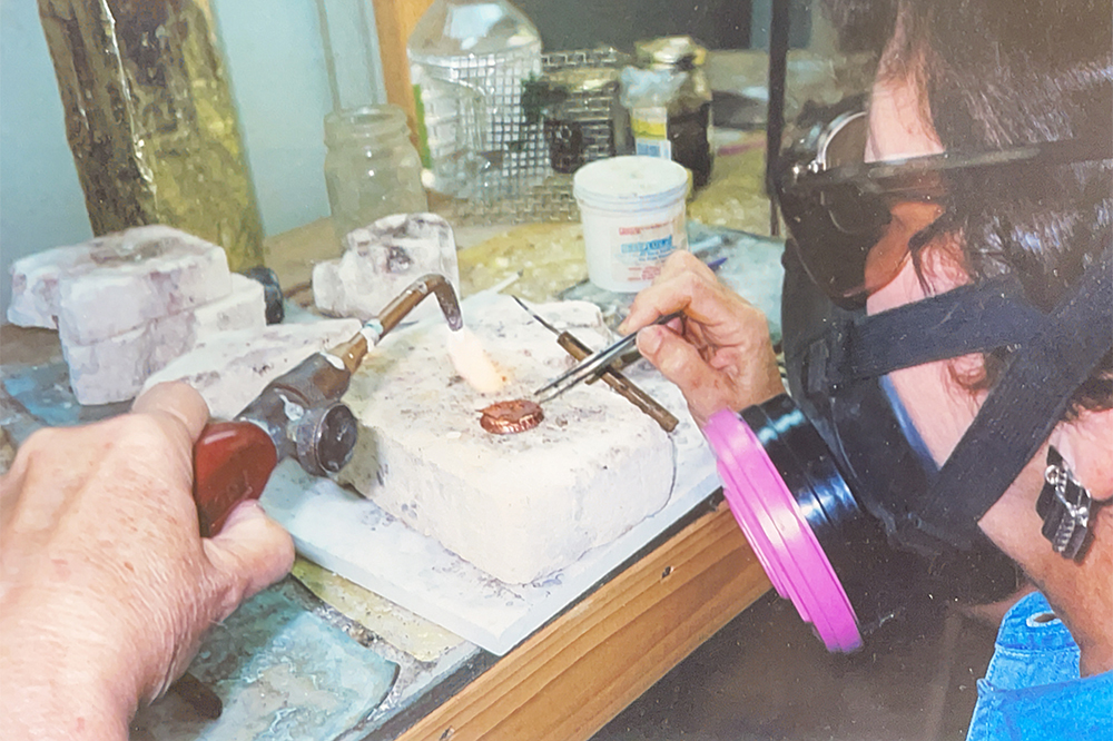 Close-up of Joanne's hands soldering a small piece of jewelry with a torch.