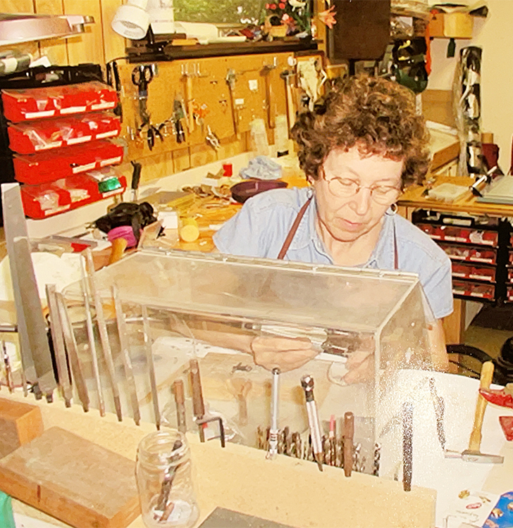 Joanne working at a drill press in her jewelry studio.